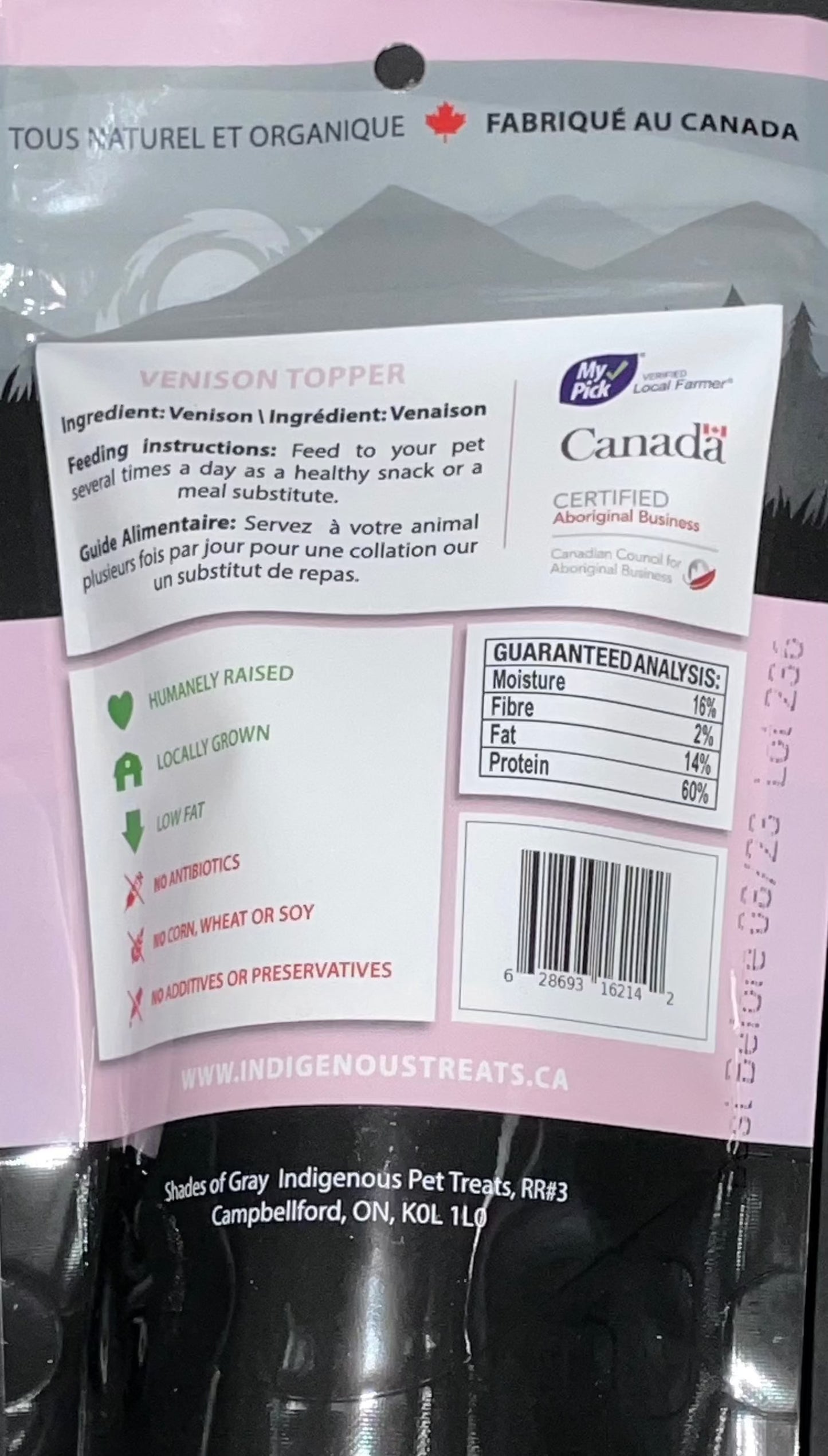 Back view of Shades of Gray Indigenous Pet Treats' Venison Topper packaging, a pink bag with 'Made in Canada' label. Highlights 100% venison, humanely raised, locally grown, low fat, no antibiotics, corn, wheat, soy, or additives. Includes feeding instructions and guaranteed analysis (16% moisture, 2% fiber, 14% fat, 60% protein).