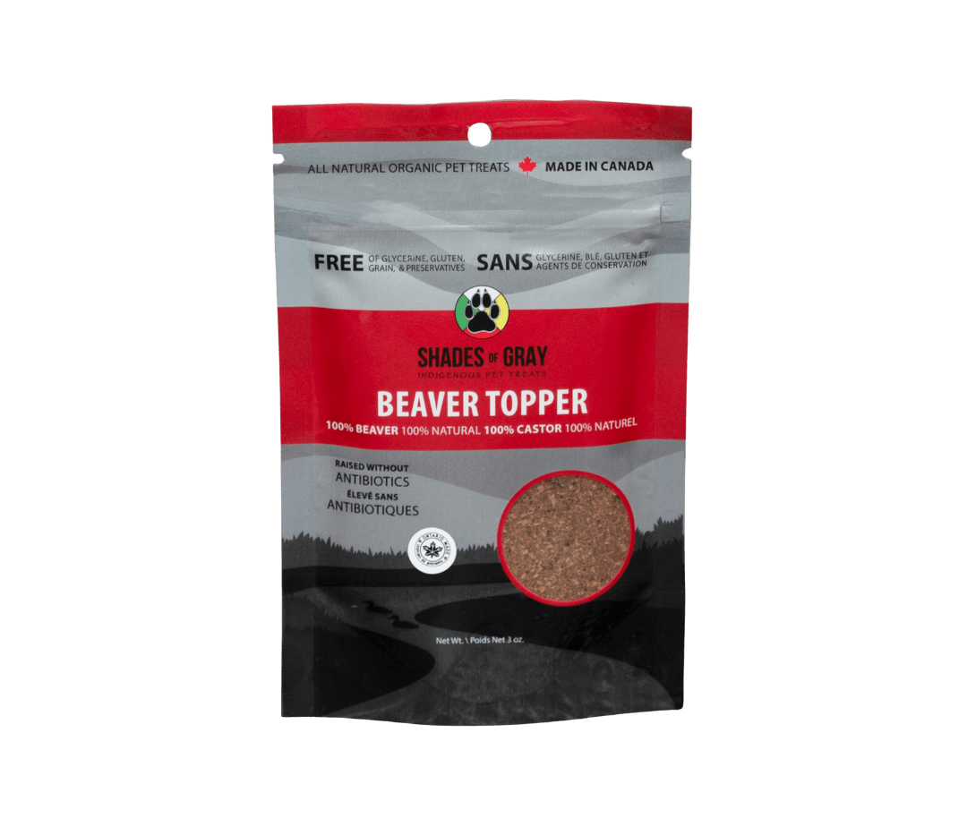 Front view of Shades of Gray Indigenous Pet Treats Beaver Topper 13 oz pouch with matte black and grey an red design, large white “BEAVER TOPPER” text, “Single Ingredient Dog & Cat Topper” subtitle, product window displaying real air-dried beaver meat in granular form, prominent Made in Ontario logo, Canadian flag icon, “100% Canadian Beaver”, and circular Shades of Gray Indigenous Pet Treats logo highlighting ethical Indigenous sourcing.