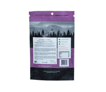 Back view of Shades of Gray Indigenous Pet Treats' Indigenous Strips packaging, a purple bag of rabbit pet treats with 'Made in Canada' label. Highlights 100% rabbit meat, humanely raised, locally grown, low fat, no antibiotics, corn, wheat, soy, or additives. Includes feeding instructions, guaranteed analysis (3% moisture, 9% fiber, 50% protein), and certifications from My Pick Local Farmer and Aboriginal Business.