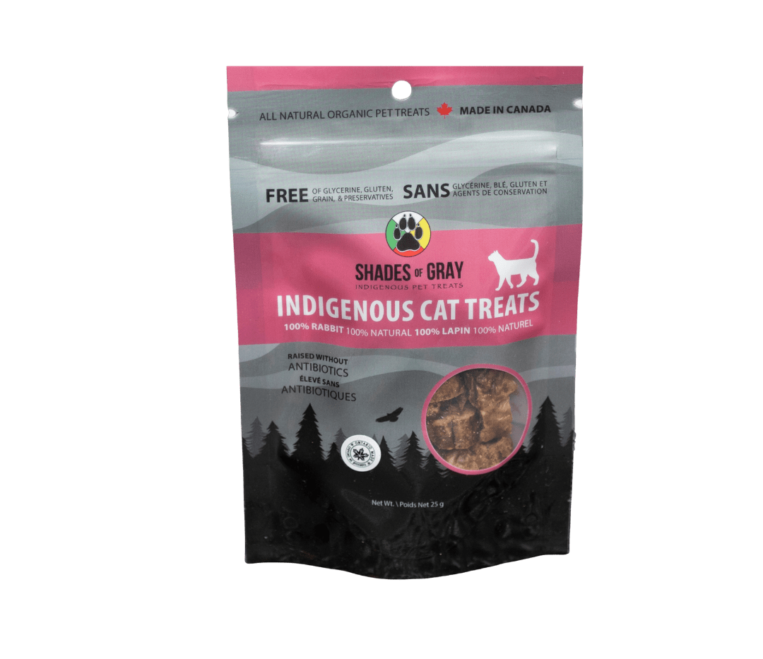 Front of Shades of Gray Indigenous Pet Treats Indigenous (Rabbit) Cat Treats packaging in pink/ black and grey resealable pouch, featuring bold “INDIGENOUS CAT TREATS” lettering, “Single Ingredient” callout, clear window showing small freeze-dried elk cubes, Made in Ontario badge, Canadian flag, and circular Shades of Gray IndigenousPet Treats logo. Bag contains Rabbit Cat Treats made with organic all natural 100% Rabbit, for your cats. Free of Glycerine, Gluten, Grain & Preservatives. 