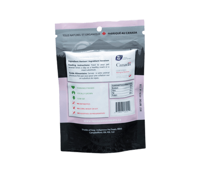 Back view of Shades of Gray Indigenous Pet Treats' Venison Topper packaging, a pink bag with 'Made in Canada' label. Highlights 100% venison, humanely raised, locally grown, low fat, no antibiotics, corn, wheat, soy, or additives. Includes feeding instructions and guaranteed analysis (16% moisture, 2% fiber, 14% fat, 60% protein).