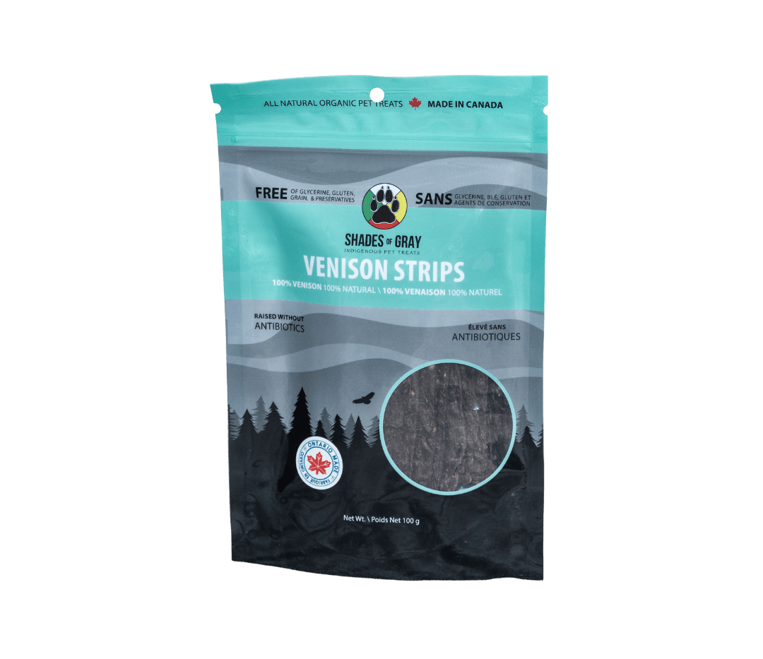 Front of Shades of Gray Indigenous Pet Treats Venison Strips packaging in premium Teal / black and grey resealable pouch, featuring bold white “VENISON STRIPS” lettering, single-ingredient callout, clear window showing long air-dried Canadian venison strips, Made in Ontario badge, Canadian flag, and circular Shades of Gray Indigenous Pet Treats logo