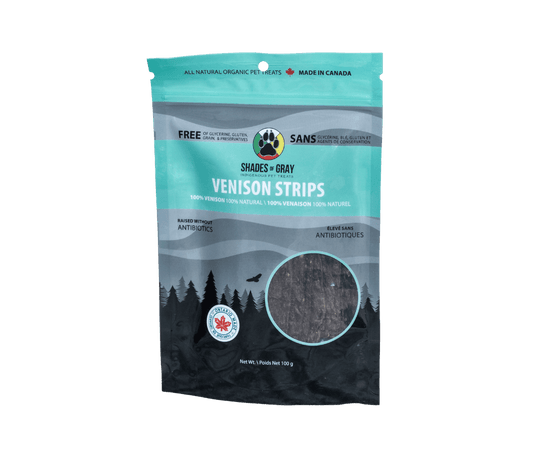 Front of a teal 100g Shades of Gray Venison Strips bag, single-ingredient venison dog treats with a window showing thin dehydrated venison strips. 100% venison, raised without antibiotics, Ontario Made.